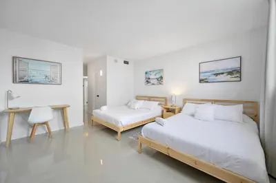 a bedroom with two beds and a desk and a table at Beautiful and big Apartment by the beach in Sunny Isles Beach