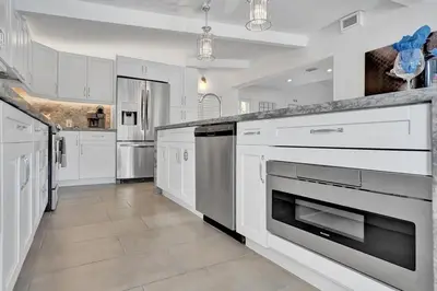 a large kitchen with white cabinets and stainless steel appliances at New ! Pool House 3-bedroom Home Victoria Park in Fort Lauderdale