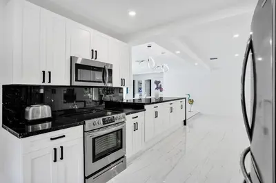 a kitchen with white cabinets and black counter tops at Hibiscus House in Fort Lauderdale