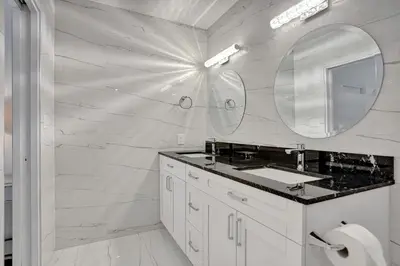 a white bathroom with a sink and a mirror at Hibiscus House in Fort Lauderdale