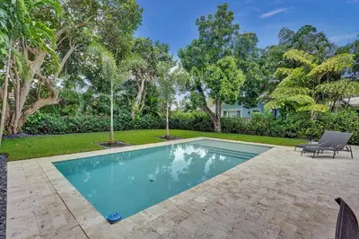 a swimming pool in a yard with trees at Hibiscus House in Fort Lauderdale