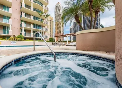 a hot tub with palm trees and a building at Modern 2 BDR at King David with Ocean View in Sunny Isles Beach