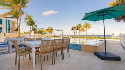 a table with chairs and an umbrella next to the ocean at Winter Rate Discount Beachside Home Pool Views Beach Haven by AvantStay in Fort Lauderdale