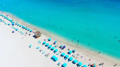 an overhead view of a beach with blue umbrellas and people at Oceanview Private Condo at 1 Hotel & Homes -1222 in Miami Beach