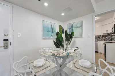 a dining room with a glass table and white chairs at Oceanfront Beach Retreat Beach Service 905 in Miami Beach