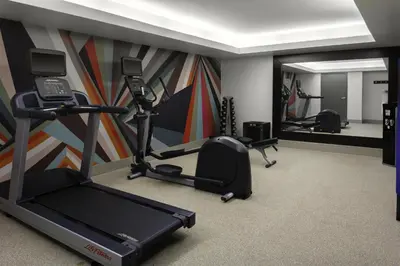 a room with a gym with a treadmill and a mirror at Hilton Garden Inn Miami South Beach in Miami Beach