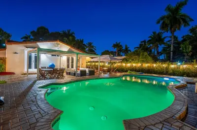 a swimming pool in front of a house at night at Coastal Paradise Retreat- Mini Golf, 4 Bedrooms, Game Room, Htd Pool, BBQ Fire Pit in Hollywood