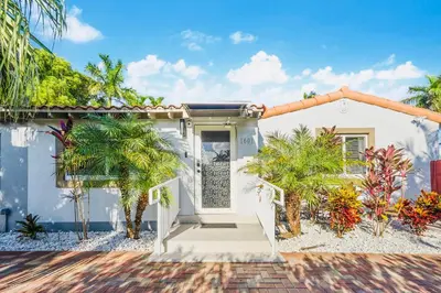 a white house with palm trees in front of it at Coastal Paradise Retreat- Mini Golf, 4 Bedrooms, Game Room, Htd Pool, BBQ Fire Pit in Hollywood