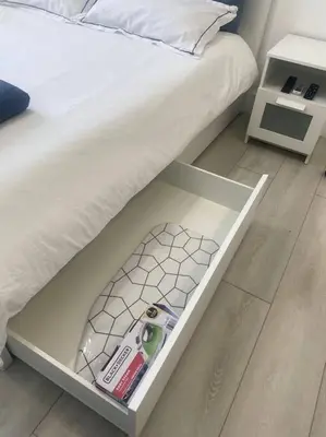 a white drawer under a bed with a book and a bed at Excellent location Miami Brickell Studio in Miami