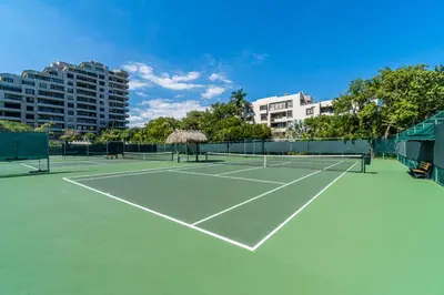 a tennis court with a net and some buildings at Tropical Retreat with Beach Resort Amenities in Miami