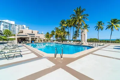 a swimming pool at the resort with palm trees at Tropical Retreat with Beach Resort Amenities in Miami