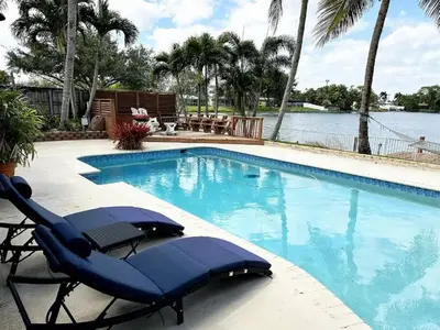 a swimming pool with two lounge chairs and the water at Inactive 193 Modern, 4B&3B with Pool and Lake in Pembroke Pines