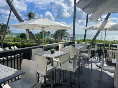 a restaurant with white chairs and tables and umbrellas at Ocean front 2 Bedroom and 2 Bathroom apartment at The Alexander Resort in Miami Beach