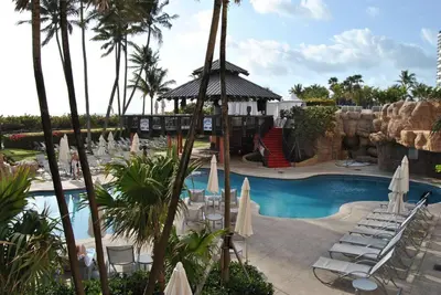 a resort with a pool with chairs and a waterfall at Ocean front 2 Bedroom and 2 Bathroom apartment at The Alexander Resort in Miami Beach