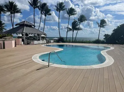 a swimming pool with palm trees and the ocean at Ocean front 2 Bedroom and 2 Bathroom apartment at The Alexander Resort in Miami Beach