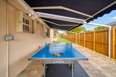 a ping pong table in the backyard of a house at Casa grande con piscina-Palmetto Eliptic Miami- in Tamiami
