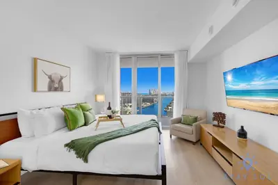 a white bedroom with a large bed and a desk at Infinite View Amazing Apt Spectacular Amenities in Hallandale Beach