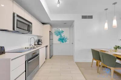 a kitchen with white cabinets and a table in it at Infinite View Amazing Apt Spectacular Amenities in Hallandale Beach