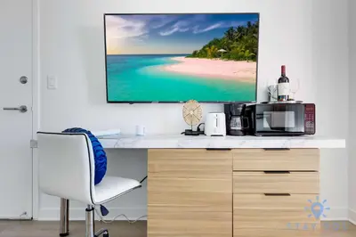 a desk with a tv on a wall with a beach at Spacious studio Amazing Amenities Infinite View in Hallandale Beach