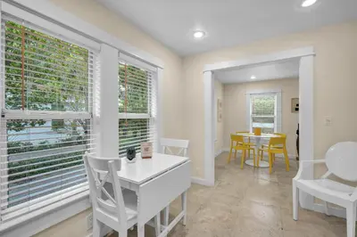 a dining room with windows and a table and chairs at Renovated Grove Bungalow -near Coconut Grove in Miami