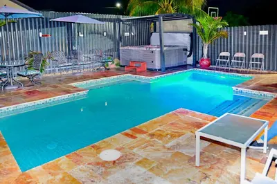 a swimming pool with a table and chairs in front of a fence at Luxury home 5 minutes from stadium in Miami