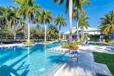 a swimming pool with palm trees and blue lounge chairs at Doral Pool 404 by Wave Properties in Miami