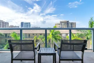 two chairs and a table on a balcony with a view at Beautiful 2BR Balcony Pool Near Beach & Fun in Hallandale Beach