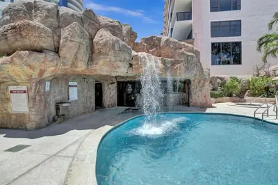 a swimming pool with a waterfall in front of a building at High Floor Miami Beach Pool Beach Service 1219 in Miami Beach