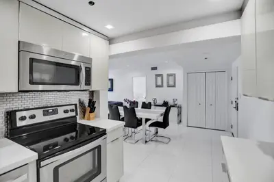 a kitchen with a microwave and a table with chairs at High floor 2BD with beach service 1616 in Miami Beach