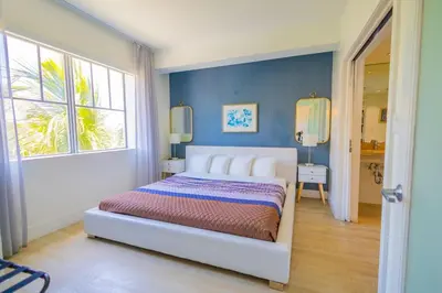 a bedroom with a white bed and a blue wall at King Bed-Apt with Rooftop Pool-Bar D303 in Miami Beach