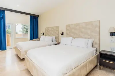 two beds in a hotel room with blue curtains at The Link Hotel South Beach in Miami Beach