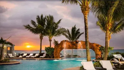 a resort with a pool with palm trees and a sunset at Deluxe Studio Balcony Bay View Amazing Pool in Sunny Isles Beach