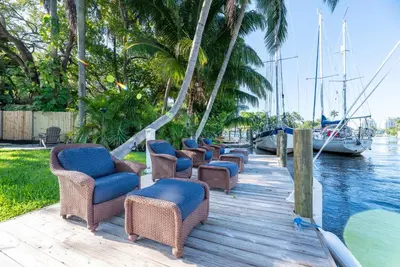 a row of chairs sitting on a dock next to the water at The Riverside Retreat 1 in Fort Lauderdale