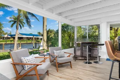 a screened porch with chairs and a table and a fireplace at The Riverside Retreat 2 in Fort Lauderdale