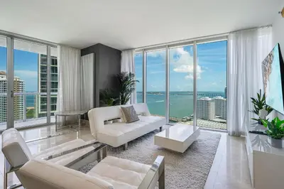 a living room with white furniture and large windows at ICON Brickell Miami- 2 bedroom Condo with City and water views! in Miami