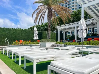 a row of white chairs and umbrellas in front of a building at 2BR Fort Lauderdale W Residence with Double Living Room, Ocean & Intercoastal Views, Brand New Sofas! in Fort Lauderdale