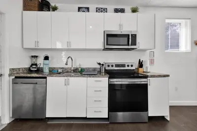 a kitchen with white cabinets and a black stove top oven at Dos Casitas Design District #1 - 3 Bedroom House in Miami