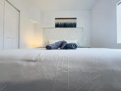 a white bed with two blue pillows on it at Dos Casitas Design District #1 - 3 Bedroom House in Miami
