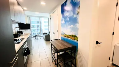 a room with a kitchen with a painting on the wall at Sky-High oasis Large Studio POOL & GYM in Miami