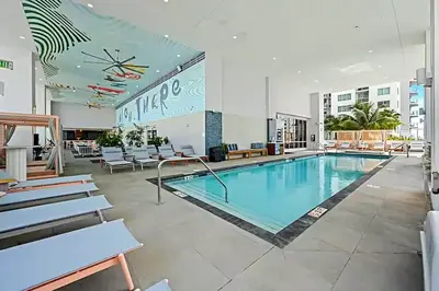 a pool in a hotel lobby with chairs and tables at Sky-High oasis Large Studio POOL & GYM in Miami