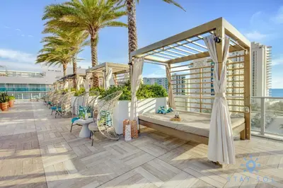 a balcony with chairs and palm trees on a building at Front Intercostal Luxury Apt View Amazing in Hollywood