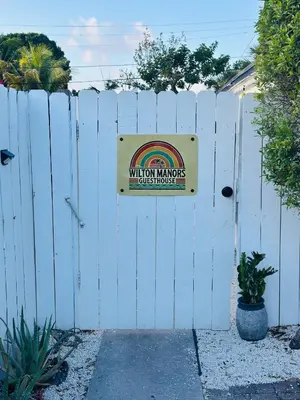 a white fence with a sign that reads wilson mons dogs house at Wilton Manors Guesthouse in Fort Lauderdale