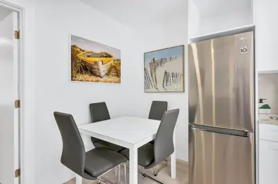 a kitchen with a white table and a stainless steel refrigerator at ULTRA Modern Apartment by the Beach in Hollywood
