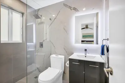 a white bathroom with a toilet and a sink at ULTRA Modern Apartment by the Beach in Hollywood