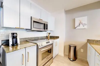 a kitchen with white cabinets and a microwave at 2 bed condo, Queen sofa bed Brickell, Free Parking, Pool, Gym in Miami