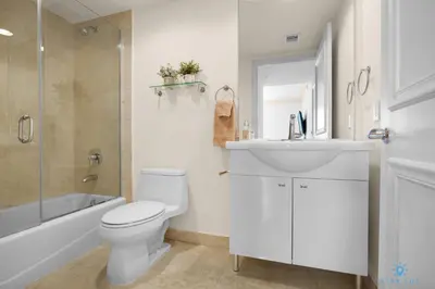 a white bathroom with a toilet and a sink at Luxury High Resort Beautiful Views & Amenities in Hallandale Beach
