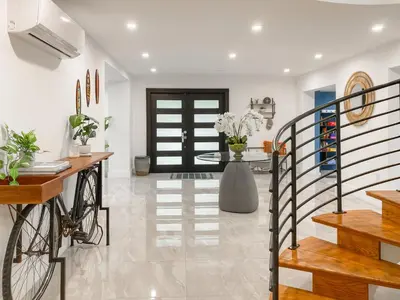 a living room with a staircase and a table with flowers at Villa Palma - Prime Location, Pool, Game Room, Outdoor Kitchen in Miami