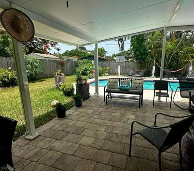 a patio with chairs and a pool in a backyard at Pool House Resort heated swimming pool private duplex in Cutler Bay