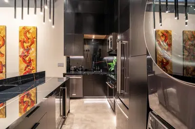 a kitchen with stainless steel appliances and black cabinets at Wynwood Condo, Walk to Restaurants and Nightclubs! in Miami