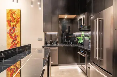 a kitchen with black cabinets and stainless steel appliances at Wynwood Condo, Walk to Restaurants and Nightclubs! in Miami
